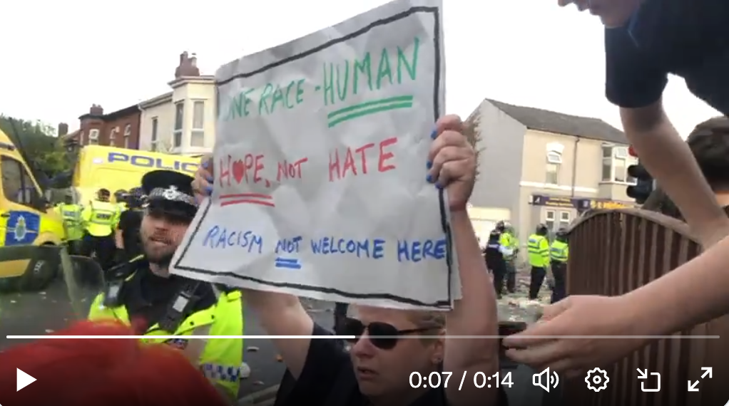 Counter protester, Southport, holding up anti-racism banner.